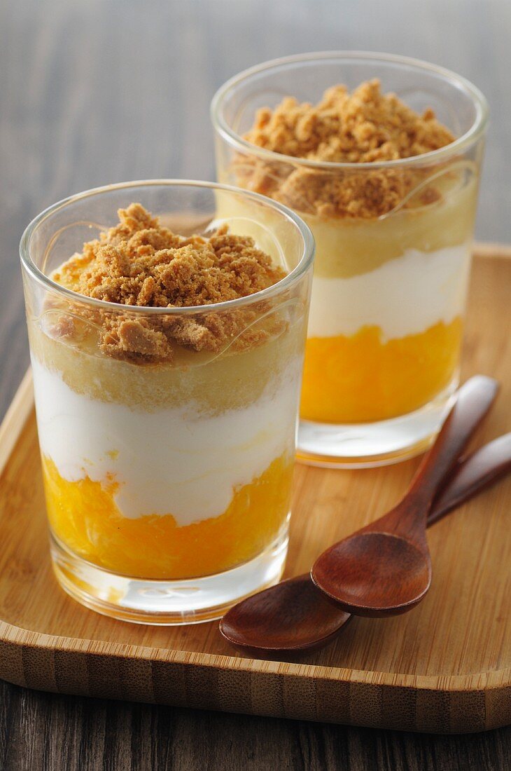 Layered desserts with orange, pear and speculoos biscuit crumbs
