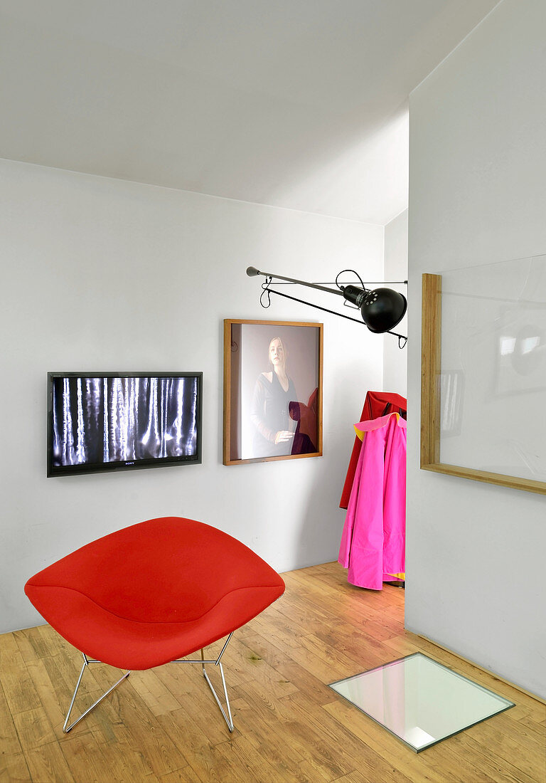 Roter Designersessel vor Fernseher und Bildern an der Wand