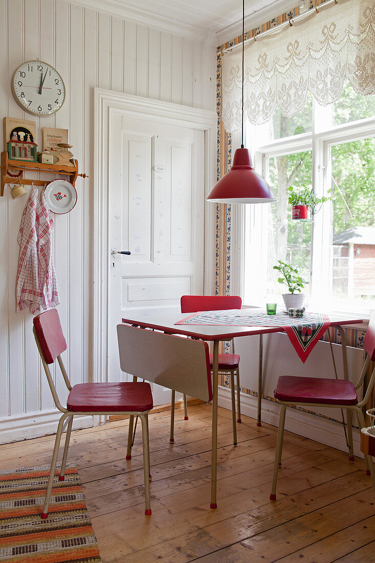 Red retro chairs around table below window in country-house kitchen