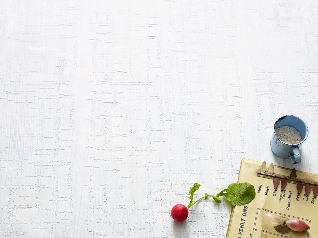 Radishes, a kitchen board and a metal cup