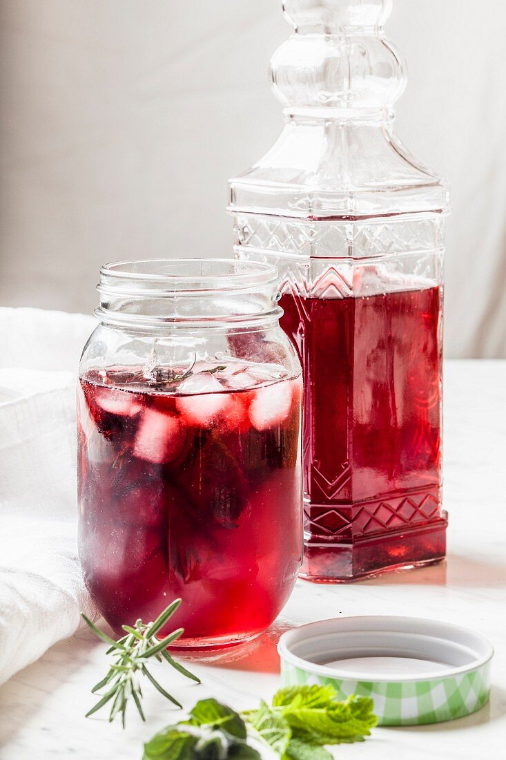 Hibiscus iced tea in a screw top glass jar and a decorative glass bottle