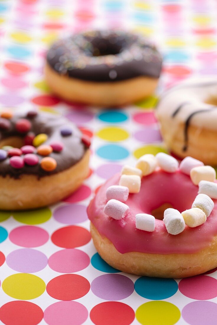 Bunt verzierte Donuts auf gepunkteter Tischdecke