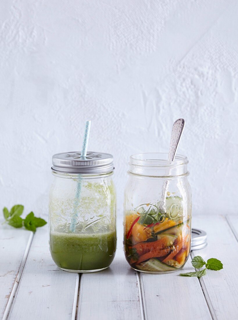 A green smoothie and a vegetable salad in glass jars (half full)