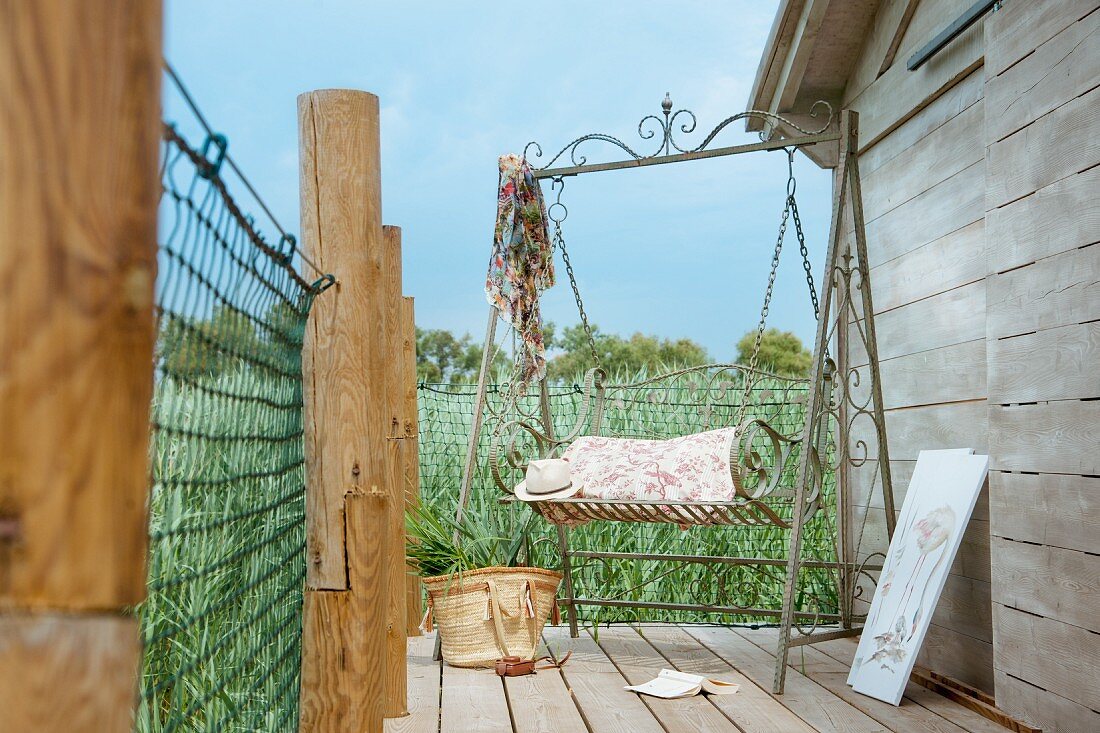 Romantisch verschnörkelte Metallschaukel auf einer Terrasse