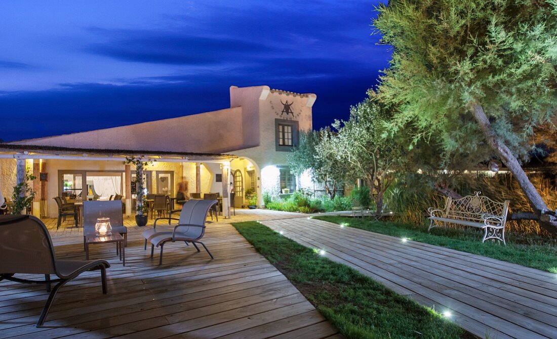 Terrasse und Weg zu einem beleuchteten Haus am Abend