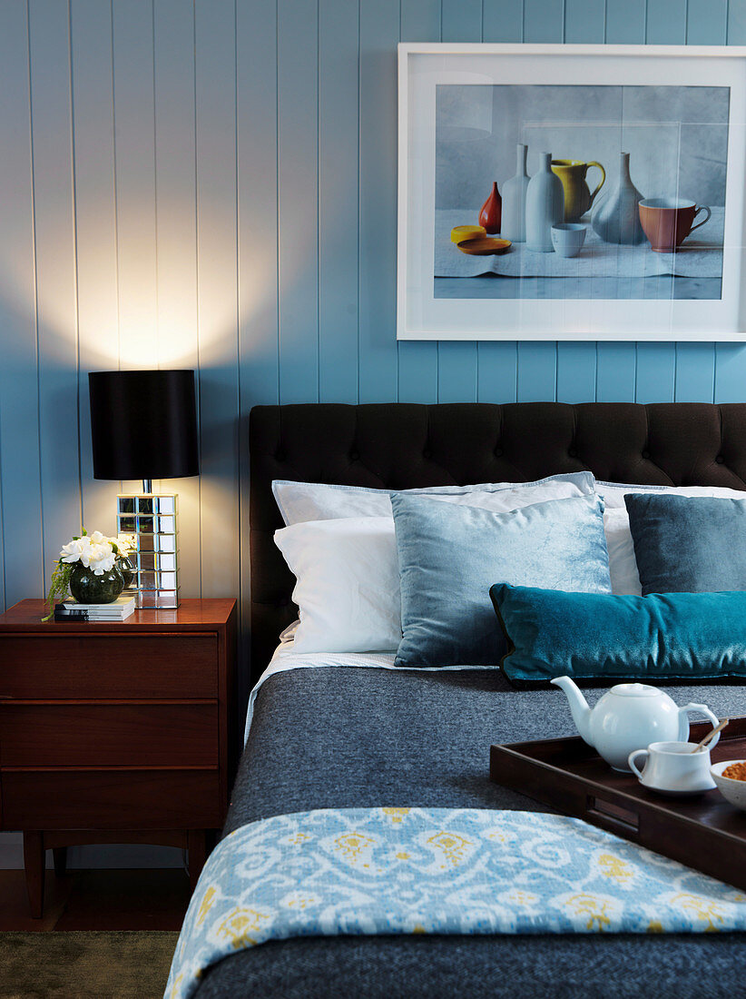 Double bed and bedside table with bedside lamp in the bedroom with wooden paneling