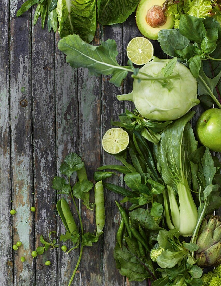 Various green fruits and vegetables on a wooden background