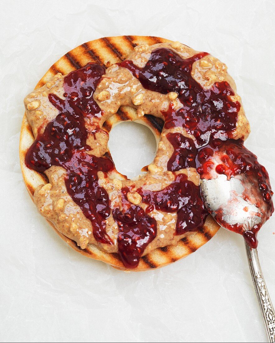 Gegrillter Bagel mit Erdnussbutter und Marmelade (Aufsicht, Nahaufnahme)