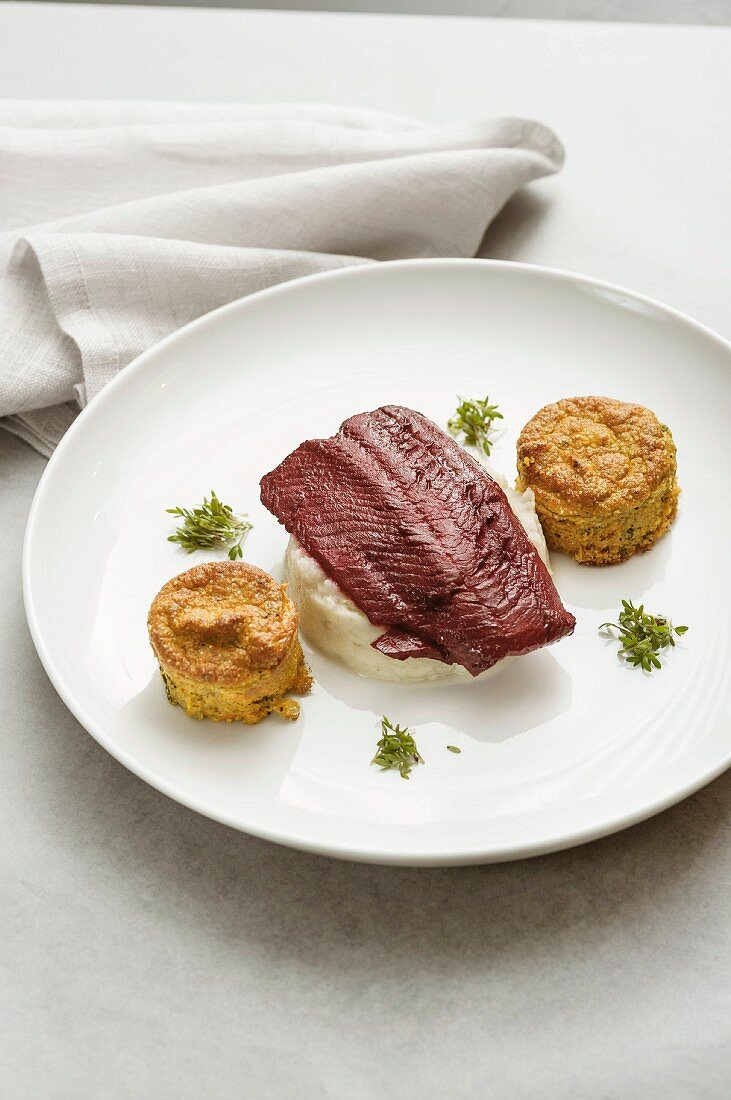 A fillet of beef poached in beetroot sauce with white celery puree, and amaranth and sweet potato cakes