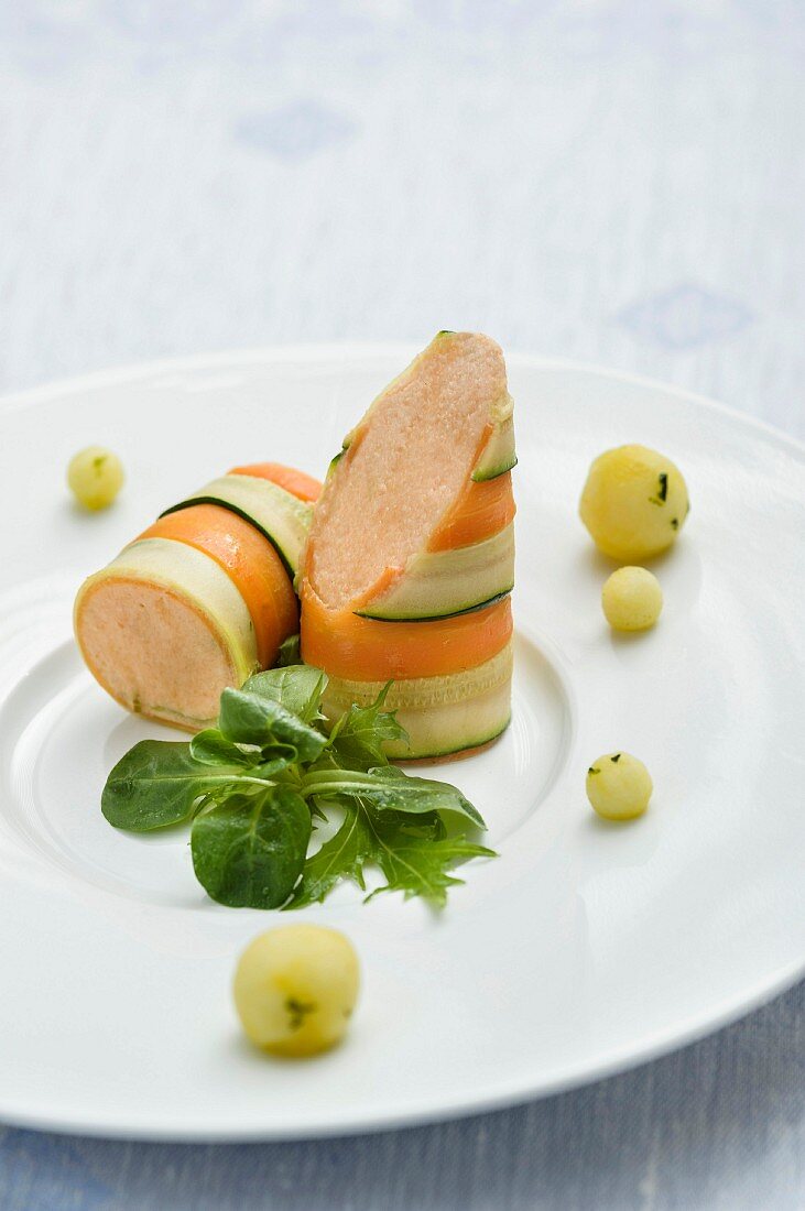 Lime, basil, and apple balls with small salmon rolls on wild herbs