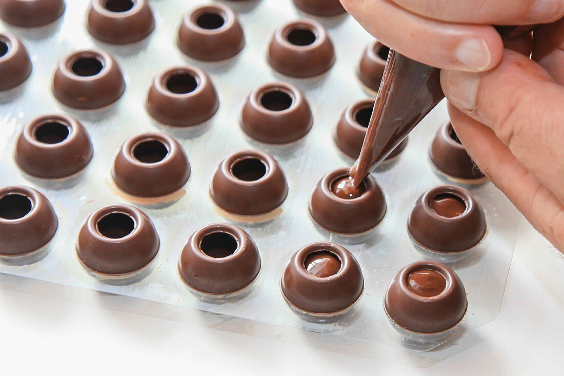 Chocolate production: pipe the filling into the hollow shells