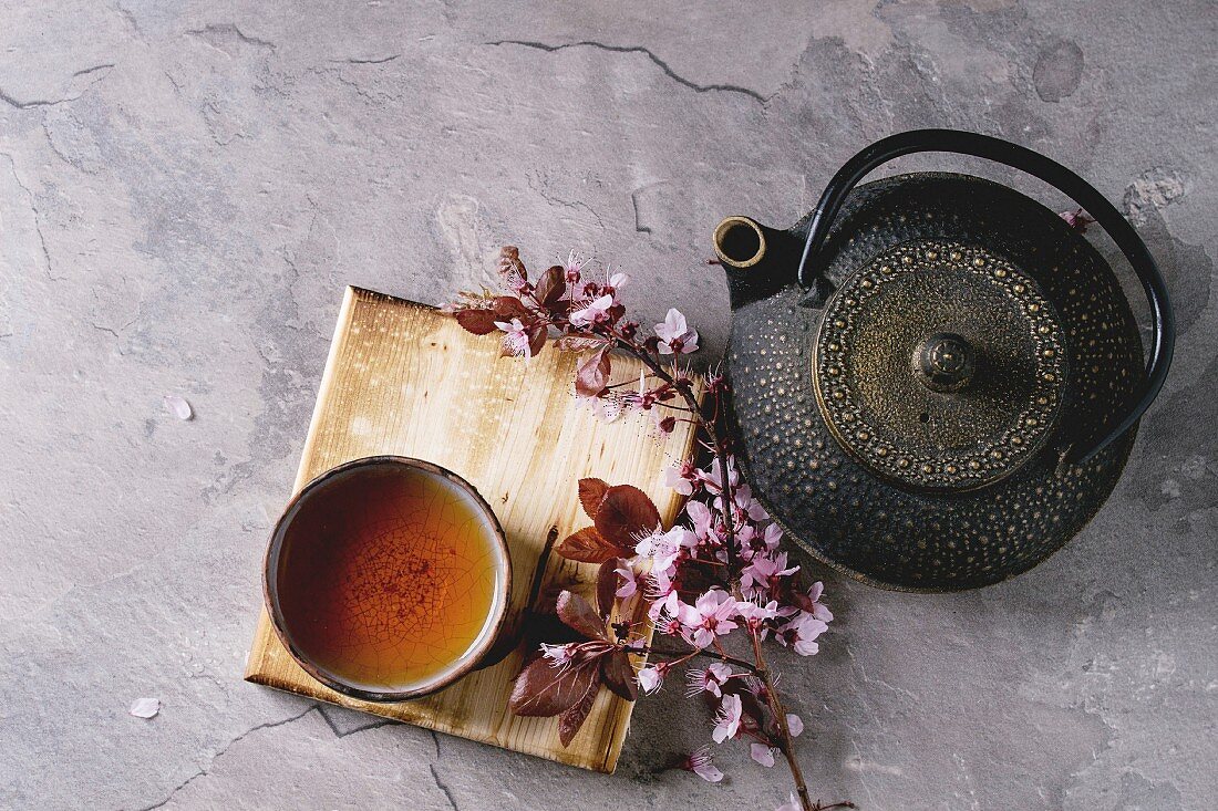An Asian teapot, a cup and cherry blossom