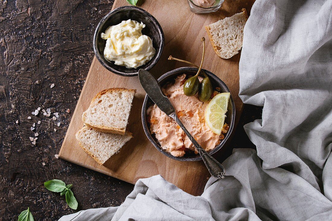 Lachscreme mit rotem Kaviar serviert mit Butter und Brot auf Holzbrett