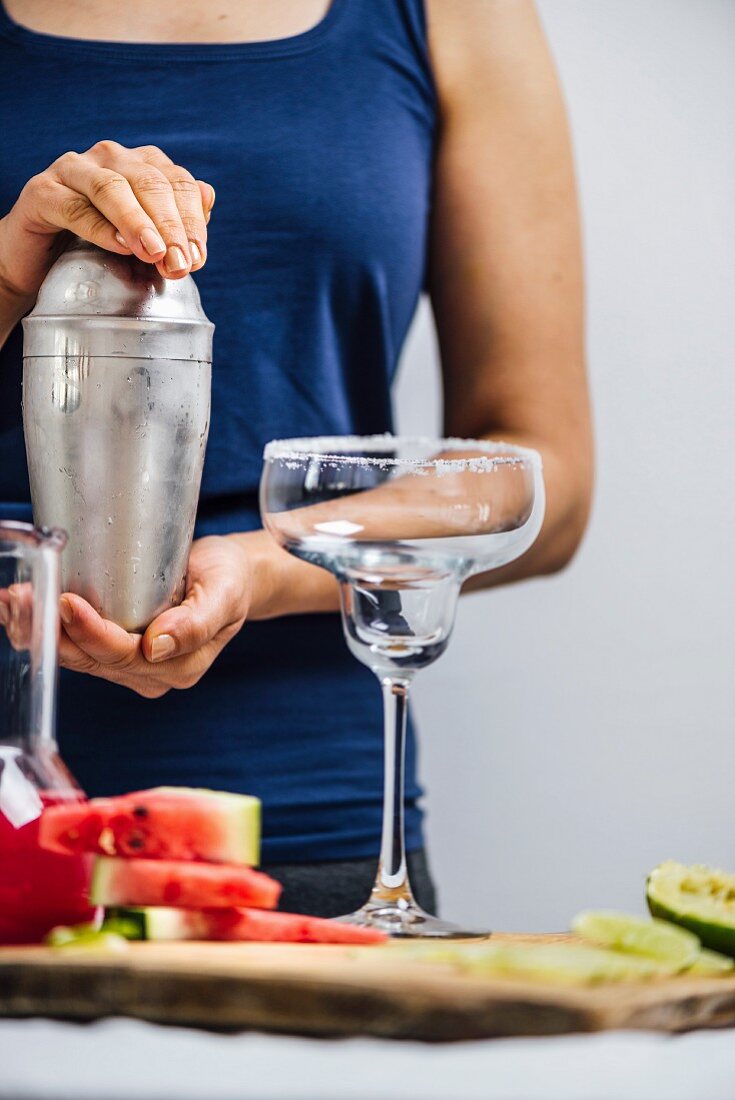 A woman preparing margarita using a shaker