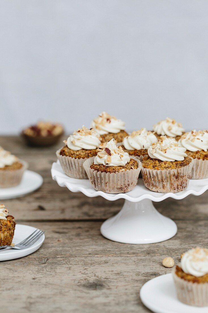 Karotten-Kokos-Cupcakes auf Kuchenständer und Tellern