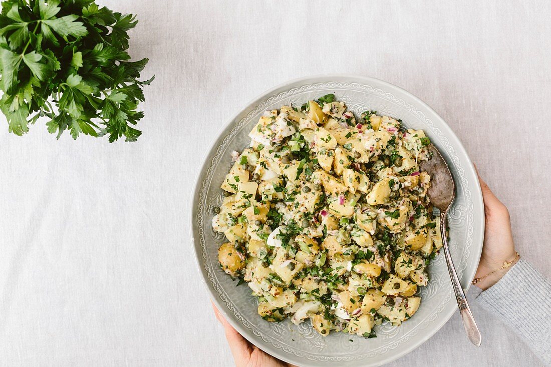 Hände halten Schüssel mit Kartoffelsalat (Aufsicht)