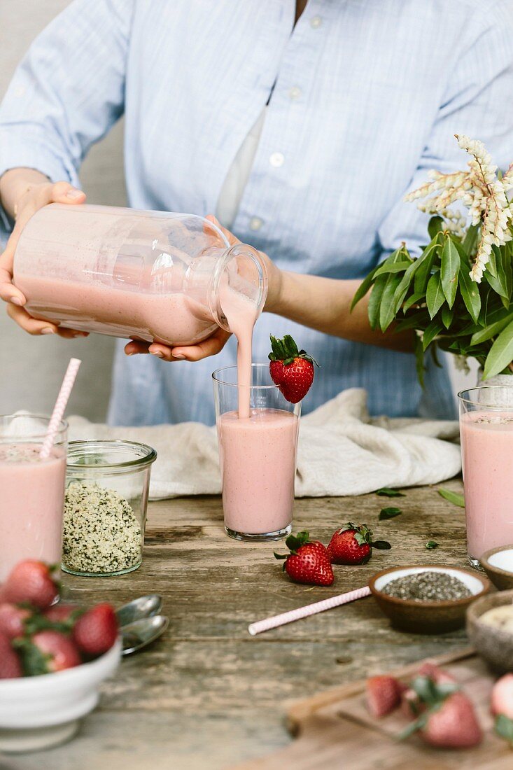 A woman is pouring smoothie in to a glass