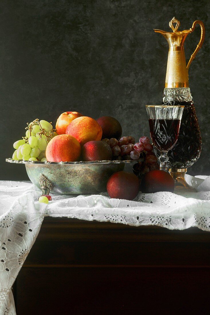 Stillleben mit Obstschale und Rotwein in Glas und Glaskaraffe