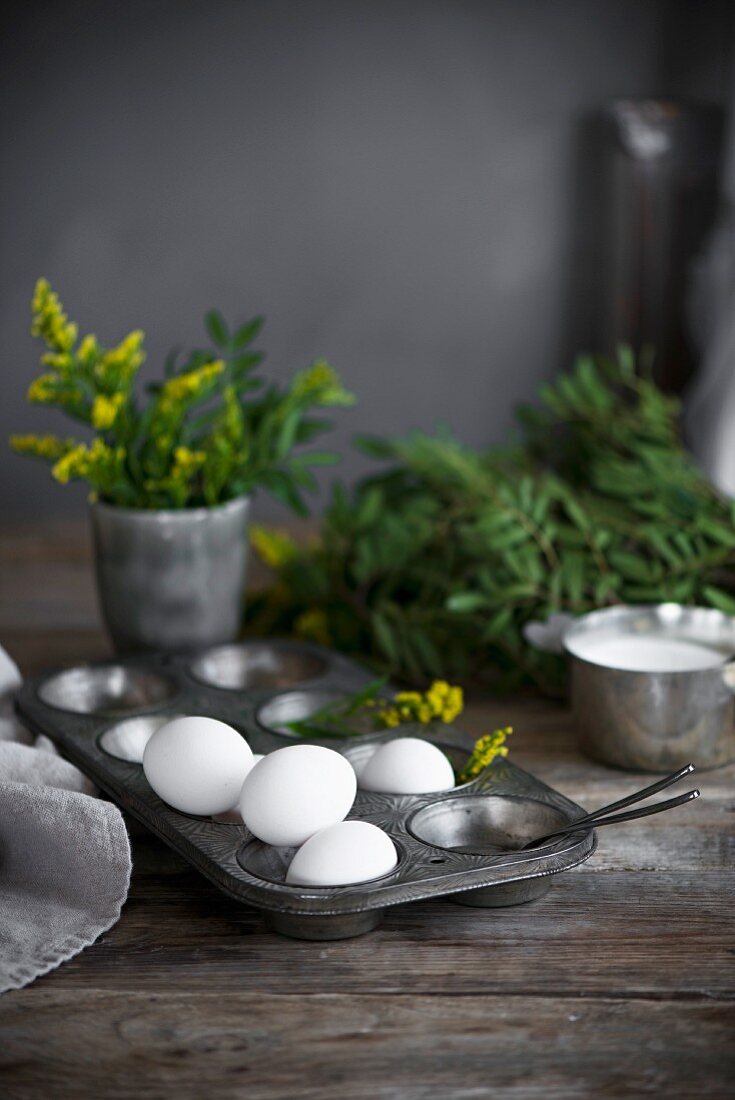 Stillleben mit weissen Eiern in Metall-Muffinform