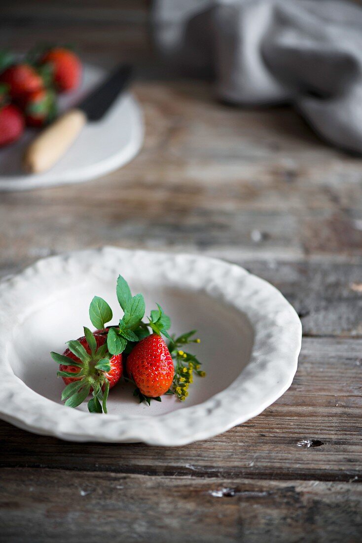 Erdbeeren in Schüssel auf rustikalem Holztisch in Landhausküche