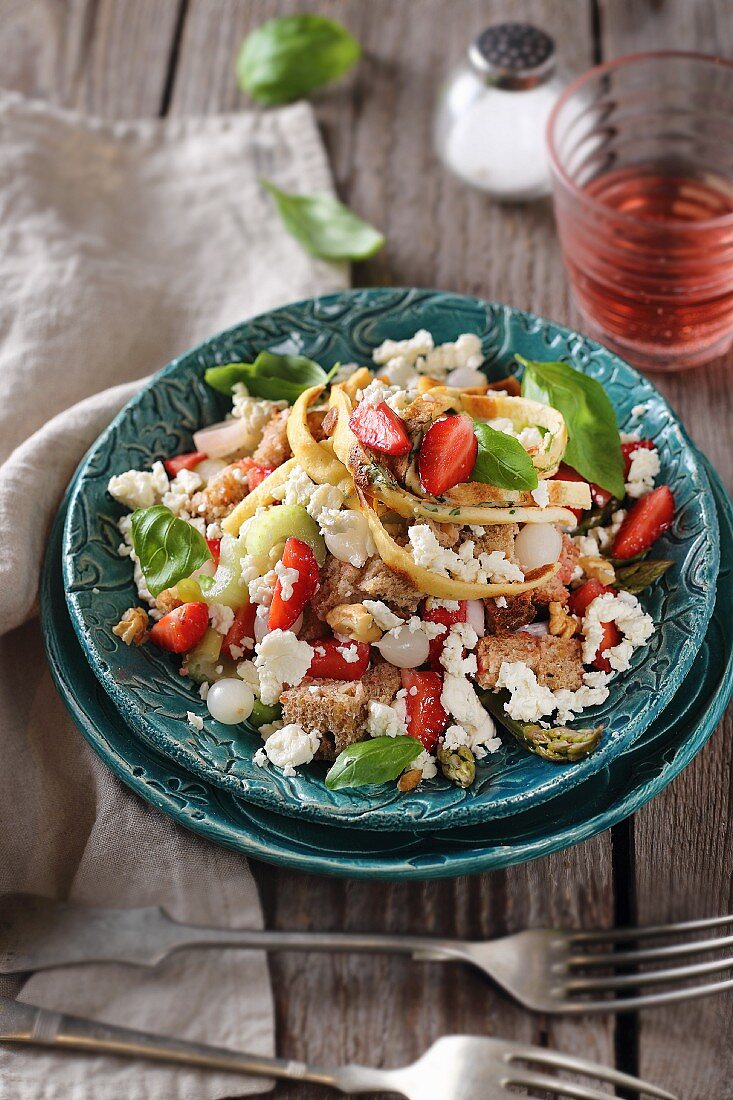 Strawberry salad with green asparagus, bread, spring onions and feta