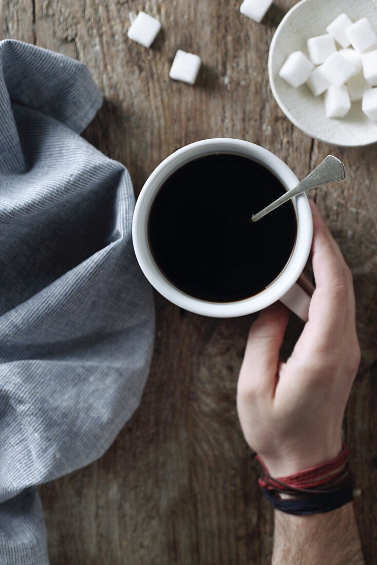 A hand holding a cup of coffee (top view)