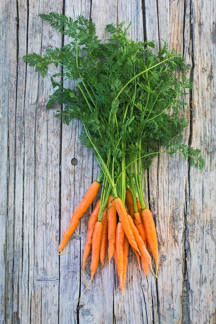 A bunch of baby carrots on a wooden surface (top view)