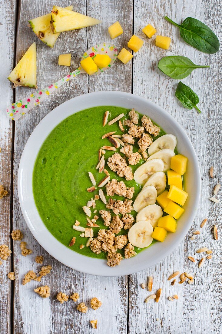A green smoothie bowl with spinach, mango, pineapple, banana and muesli
