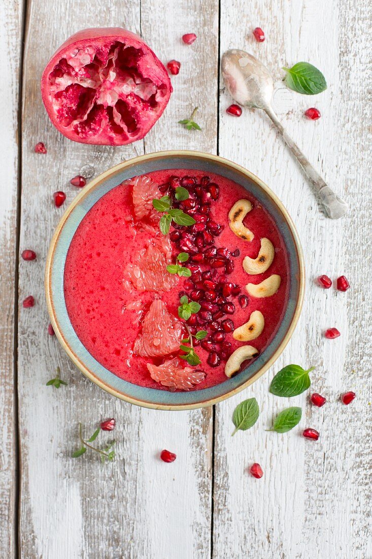 Rote Smoothie-Bowl mit Grapefruit, Himbeeren, Granatapfelkernen und Cashewnüssen