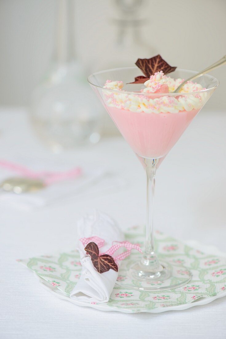 Pink crème dessert with whipped cream in a cocktail glass