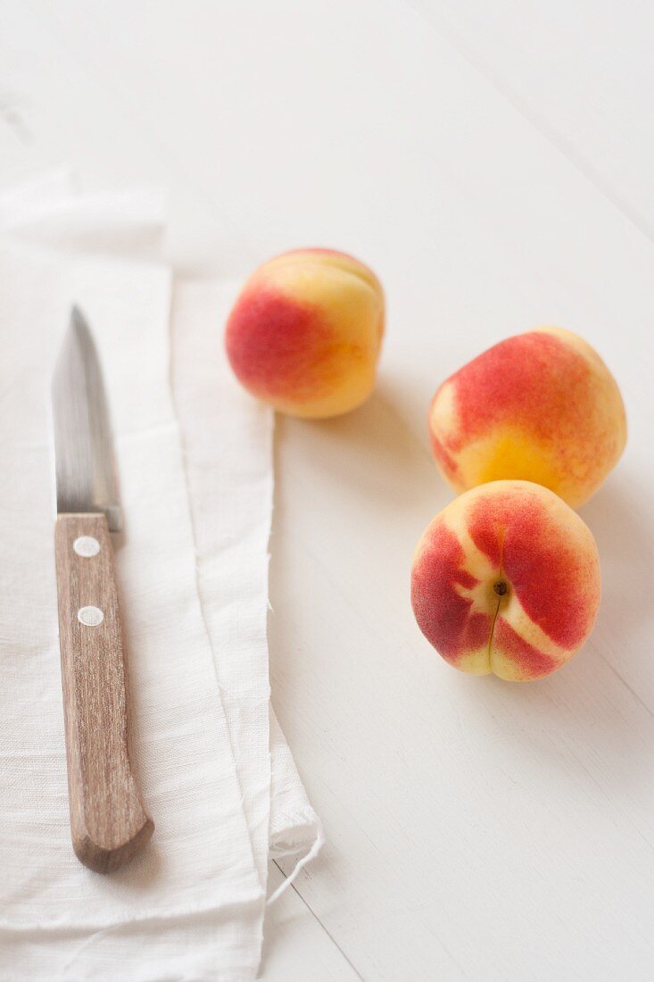 Three apricots with a cloth and a knife