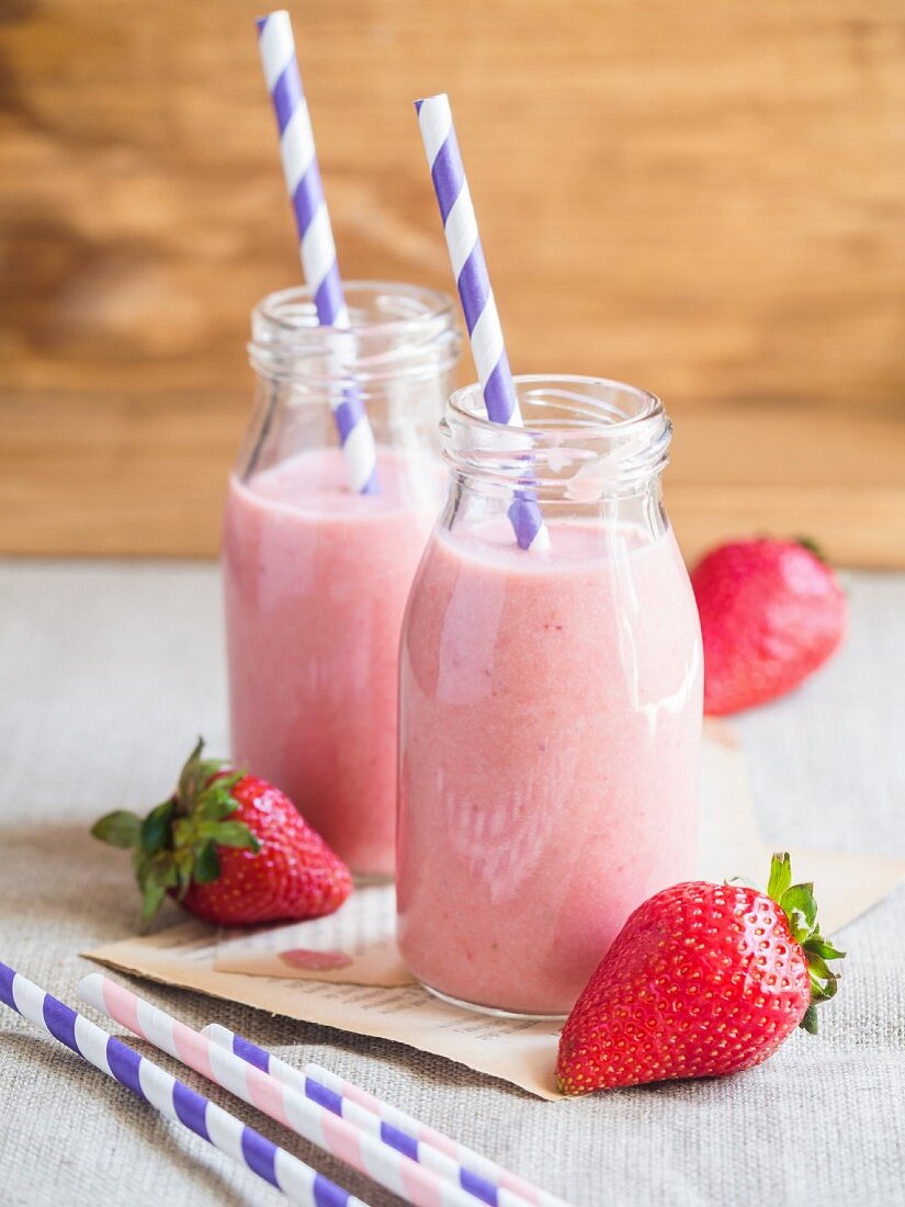 Strawberry smoothies in glass bottles with drinking straws