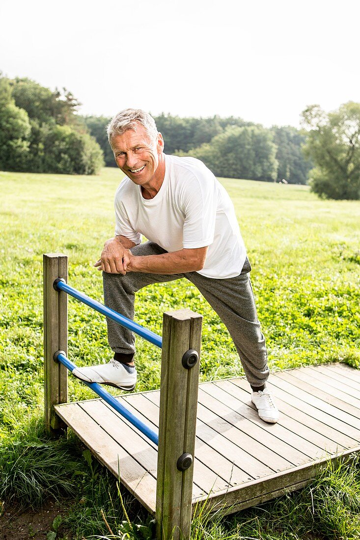 Man leaning on gate, smiling