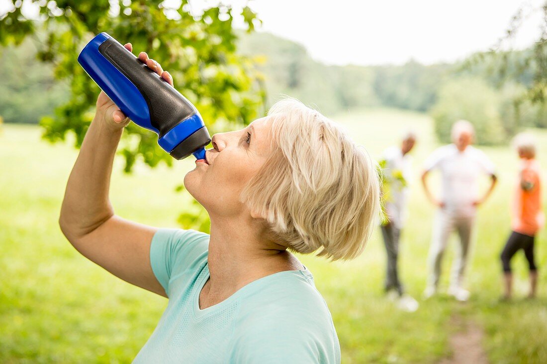 Senior woman drinking water from sports bottle
