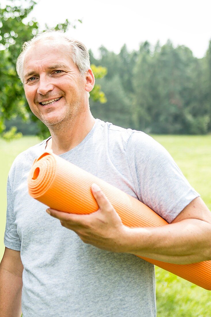 Man with yoga mat, smiling