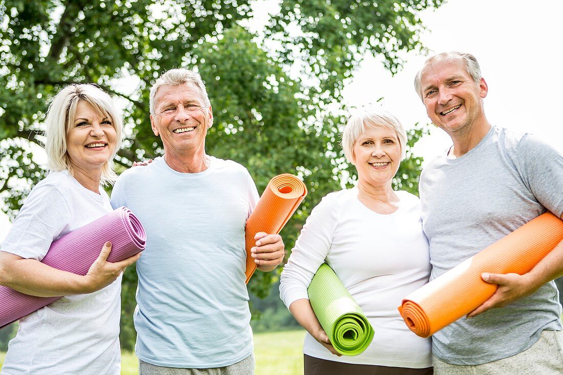 Four people with yoga mats, smiling