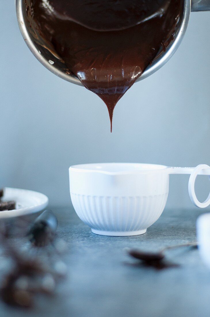Dark chocolate cream pouring into a small bowl