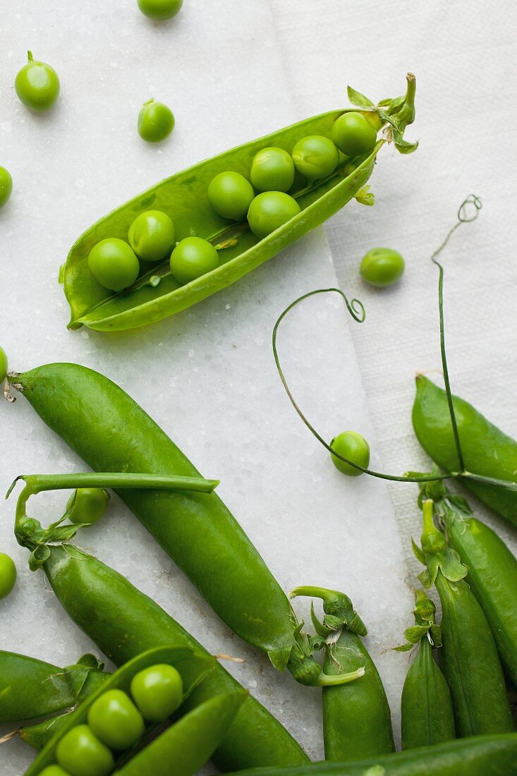 Fresh shelled peas on pale marble and linen background