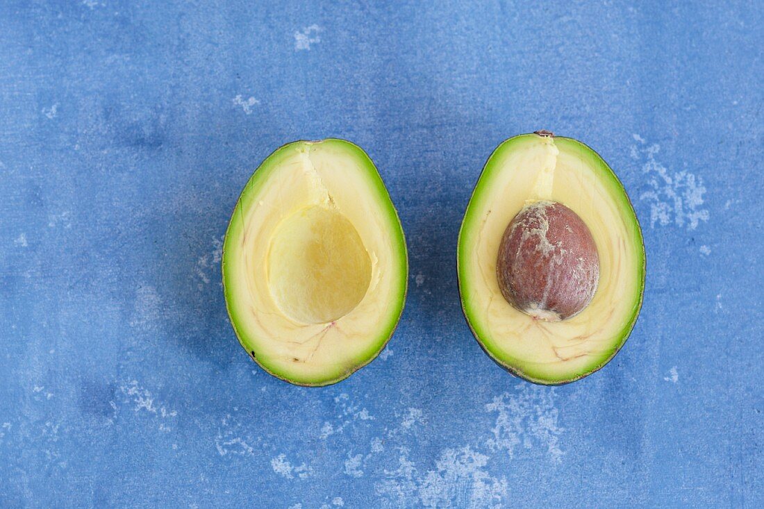 A halved avocado on a blue background