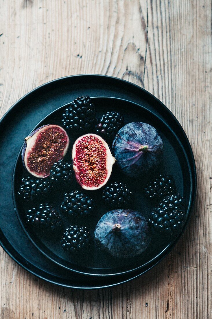 Blackberries and figs on a black plate (top view)