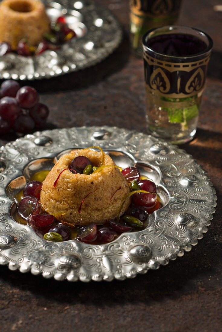 Honey semolina cakes with saffron, dark red grapes and green pistachios