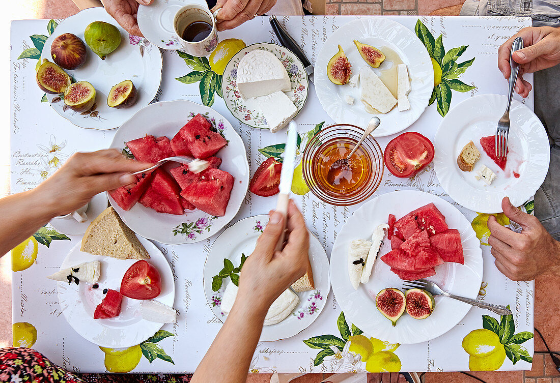 Sommerlicher Frühstückstisch mit Käse, Melone, Feigen und Kaffee