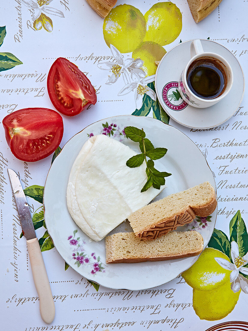 Sommerliches Frühstücksgedeck mit Halloumi, Brot, Tomaten und Kaffee