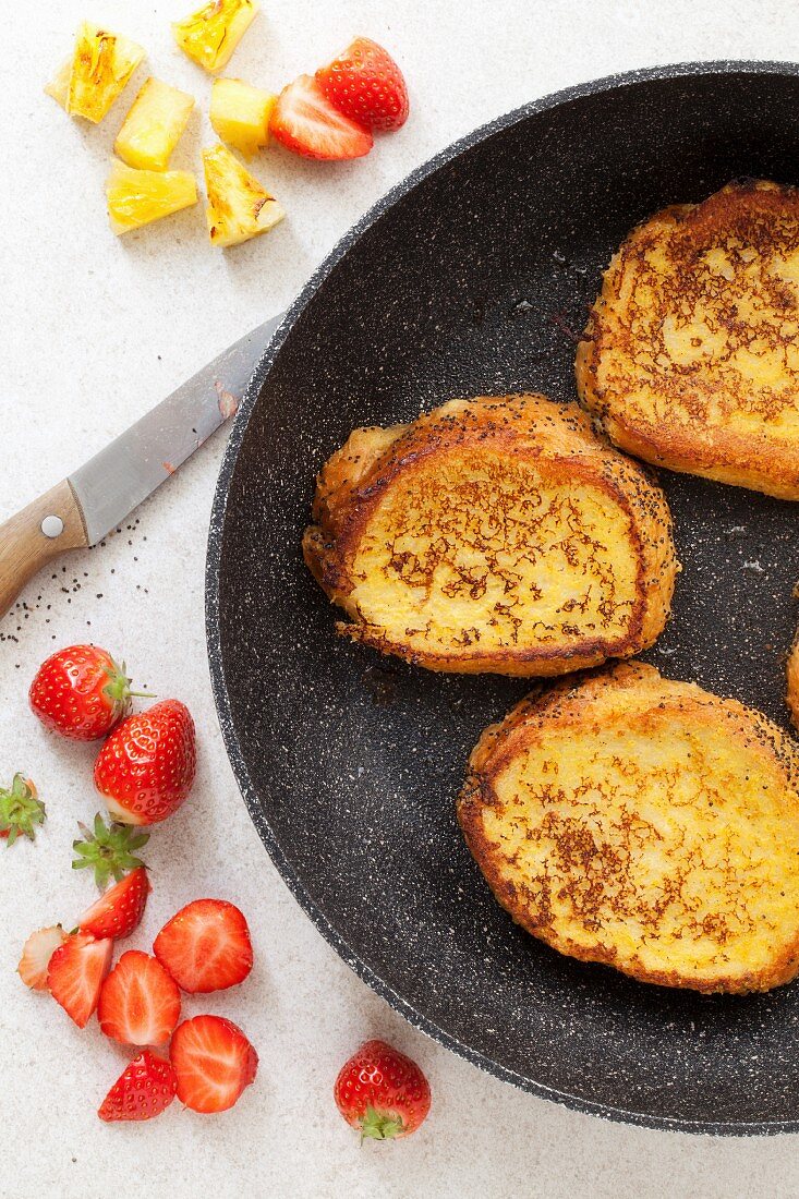 Vegan French toast in a pan with pineapple and strawberries