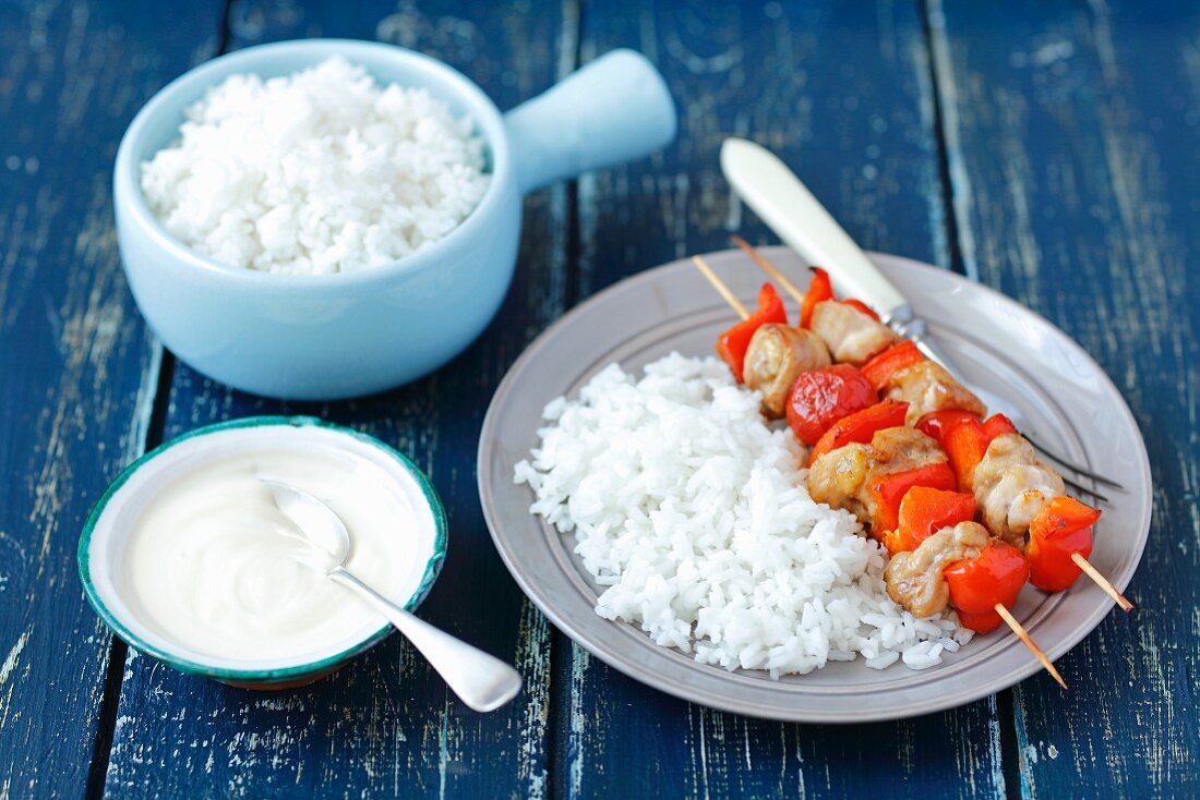 Chicken skewers with cherry tomatoes and pepper served with rice and a yoghurt dip