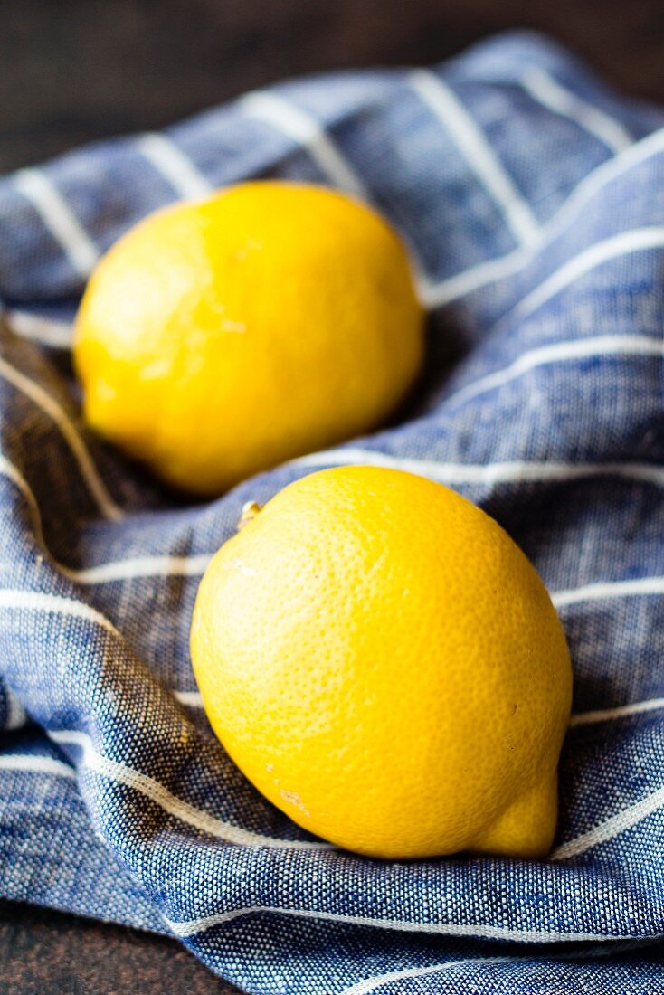 Two lemons on a blue and white striped linen cloth