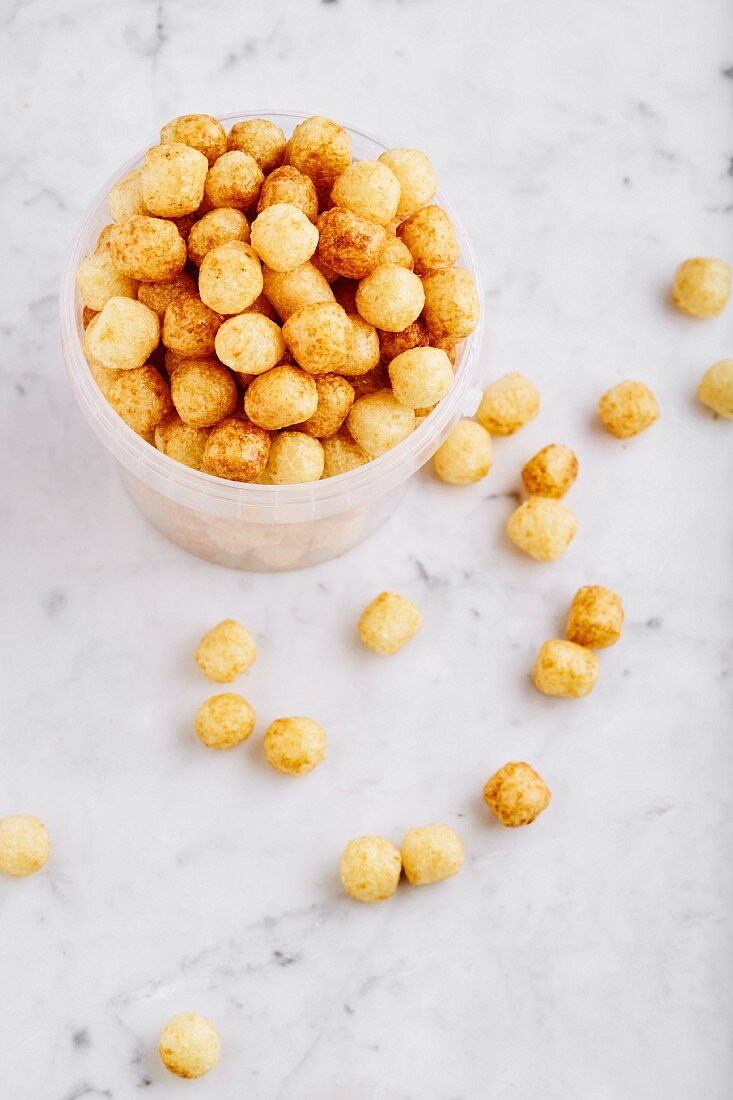 Corn pops in a plastic tub and on a marble background