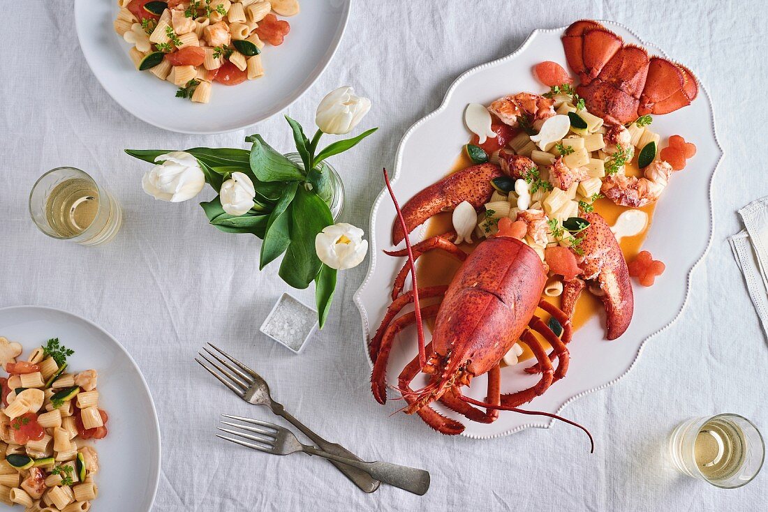 Lobster with rigatoni on a table decorated with a vase of tulips (seen from above)