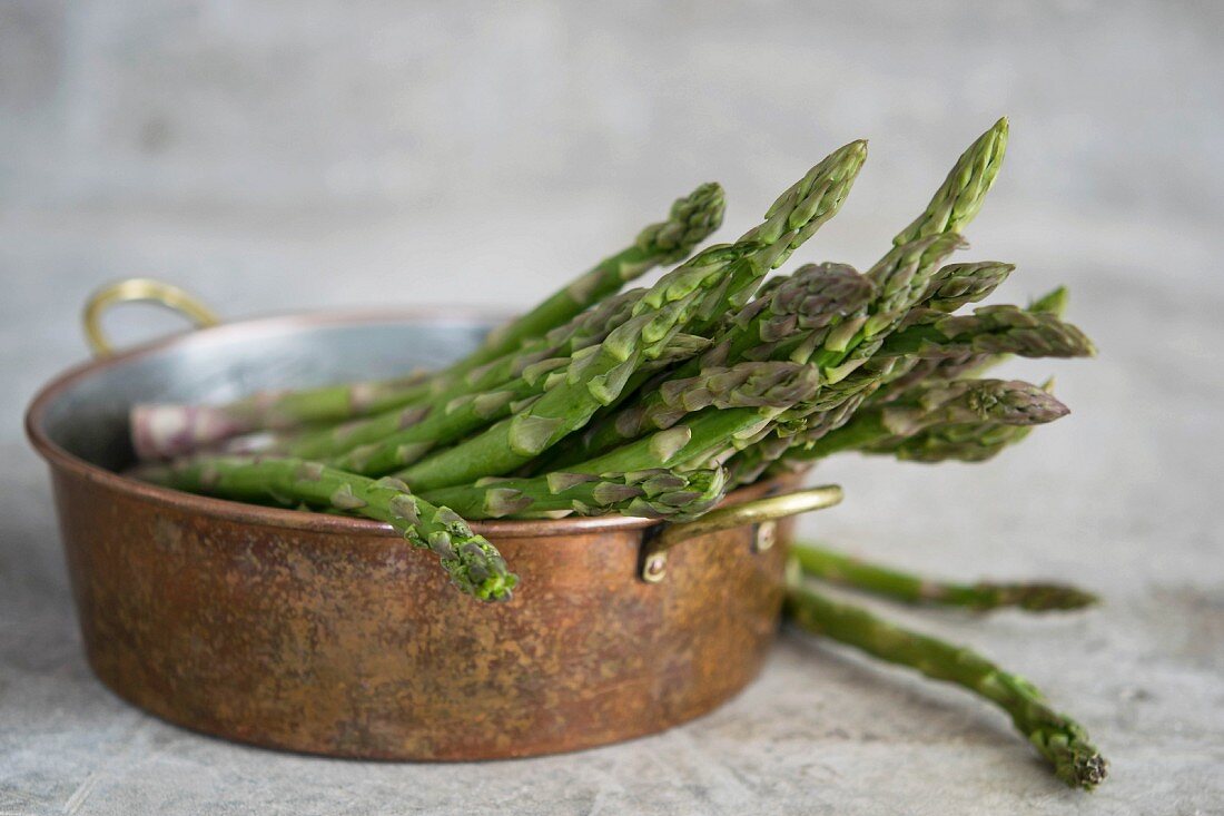 Fresh green asparagus in a metal bowl