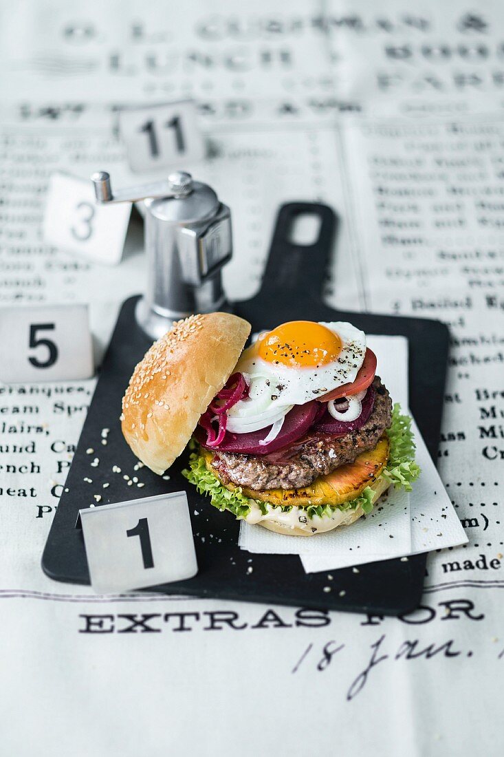 A burger with beef, a fried egg, pickled beetroot, and pineapple slices